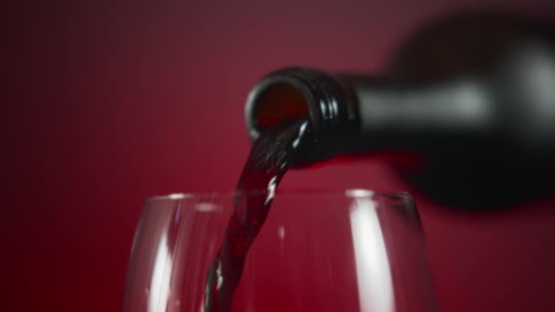 Kırmızı Arka Planda Şarap Bardağına Kırmızı Şarap Döken Bir Şişeyi — Stok video