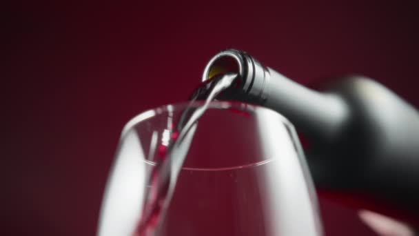 Kırmızı Arka Planda Kırmızı Şarap Şişeden Bardağa Dökülüyor Yavaş Çekim — Stok video