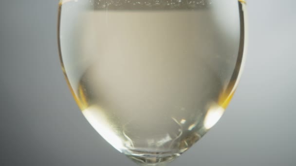 在一个灰色背景的装满白葡萄酒的酒杯旁 慢动作 — 图库视频影像
