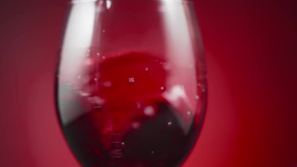 Close Red Wine Waving Wineglass Red Background Slow Motion — Stock video