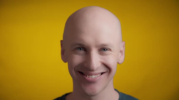 黄色の背景に大きな笑顔でカメラに向かってまっすぐ見て 彼の頭を持ち上げる青い目と明るい肌を持つ男 リアルタイム — ストック動画
