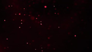 Siyah bir ekranın üzerine koyu kırmızı parçacıklar yavaşça sağdan sola doğru düşüyor. İzole kaplama.