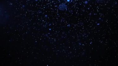 Mavi parçacıklar siyah bir arkaplan üzerine yavaşça sağdan sola düşüyorlar. İzole kaplama.