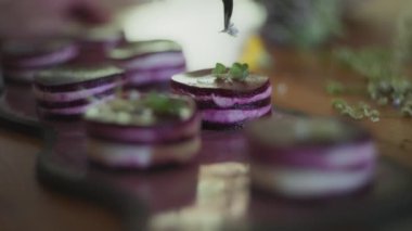 Şef, cımbızla yenebilir çiçekleri bir gurme tabağına yerleştiriyor. Yavaş çekim, yüzeysel alan derinliği. 