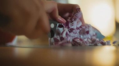 Şef kırmızı soğanı tezgahın üstünde bıçakla kesiyor. Yavaş çekim, yüzeysel alan derinliği. 