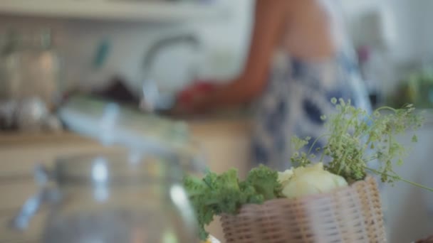 女人在厨房里洗手 前面的篮子里装着绿色蔬菜 慢动作 场浅层深度 — 图库视频影像