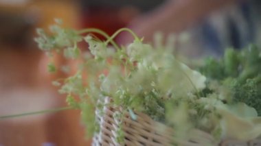 Mutfak masasındaki hasır sepetteki yenilebilir beyaz çiçekleri kapat. Yavaş çekim, yüzeysel alan derinliği. 