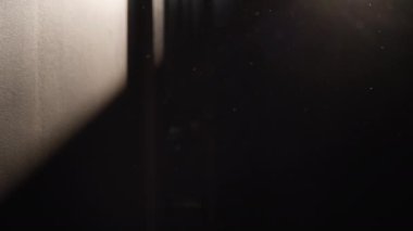 Camdan gelen güneş ışığı havada yüzen parçacıklarla duvarda parlıyor. Yavaş çekim. 