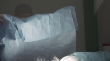 Erkek bir veteriner ameliyattan önce bir köpeğin üzerine cerrahi kılıf yerleştiriyor. Yavaş çekim. 