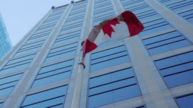Vancouver şehir merkezindeki yüksek bir binanın cam cephesinde Kanada bayrağı sallanıyor. Yavaş çekim. 