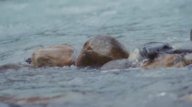 Dağ nehri kayaların arasından akıyor. Ağır çekim, yakın çekim..