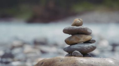 Nehir kıyısına yakın istiflenmiş dengeli taşları kapatın. Yavaş çekim. 