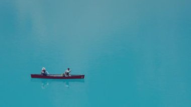 Moraine Gölü, Kanada - 15 Temmuz 2023: Yazın Moraine Gölü 'nün turkuaz sularında çift kanosu. Yavaş çekim. 