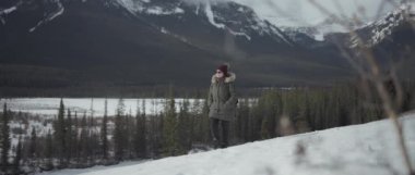 Güneşli bir kış gününde Kanada Rocky Dağları 'nda yürüyüş yapan bir kadın. Yavaş çekim. 