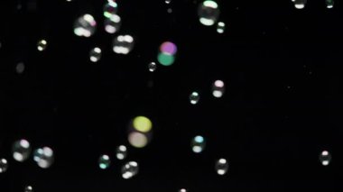 Siyah arka planda uçuşan renkli sabun köpükleri. Üst üste, arka plan. Yavaş çekim. 