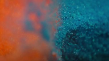 Teal ve portakal parçacıkları yavaş çekimde patlıyor. 