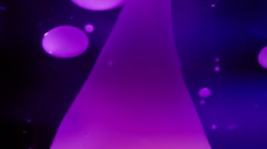 Mor lav kabarcıkları koyu mavi arka planda sıvı halinde akıyor. Yavaş çekim, soyut. 