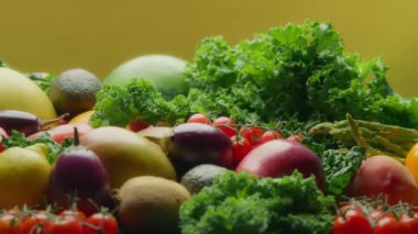 Sarı arka planda meyve ve sebze çeşitleri. Yavaş çekim, doli atış.. 