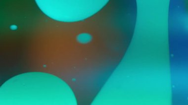 Yeşil lav kabarcıkları renkli arka planda sıvı içinde akıyor. Yavaş çekim, soyut. 