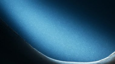 Mavi ışık yavaş çekimde yüzen toz parçacıkları üzerinde parlıyor. Soyut makro çekim. 