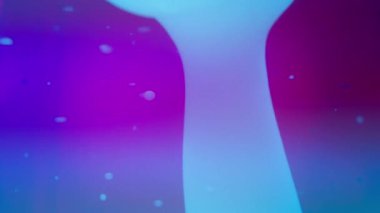 Soyut mavi lav kabarcıkları mor arkaplandaki sıvıda akıyor. Yavaş çekim.