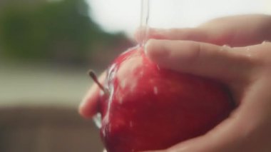 Mutfak lavabosunda kırmızı elmanın üzerine su sıçrıyor. Yavaş çekim. 