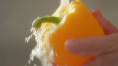 Sarı dolma biberin musluk suyunun altında yıkanmasına yakın. Yavaş çekim. 