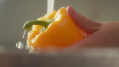 Musluk suyunun altında biber yıkayan kadınların ellerini kapatın. Yavaş çekim.