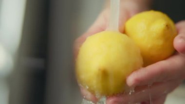 Mutfak lavabosundaki sarı limonların üzerine su sıçrıyor. Yavaş çekim. 