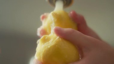 Kadınların ellerinin mutfak lavabosunda limon yıkarkenki düşük açılı görüntüsü. Yavaş çekim. 