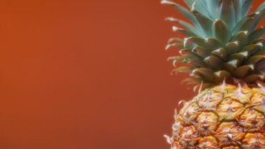 Turuncu arka planda dönen ananas. Yavaş çekim. 