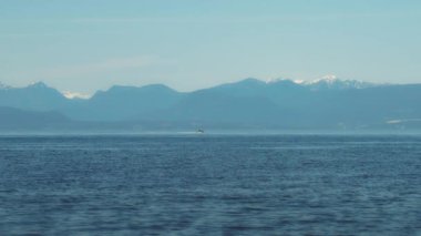 Arkasında karlı dağ zirveleri olan açık okyanusta bir sürat teknesi. Yavaş çekim.