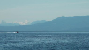 Arkasında karlı dağlar olan açık okyanusta bir sürat teknesi. Yavaş çekim.