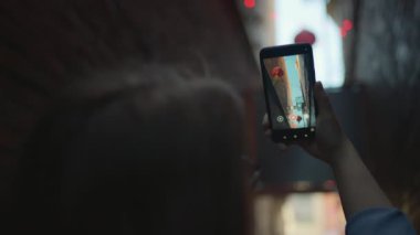 Dar sokakta yürürken telefonuyla video çeken bir kadın. Yavaş çekim.