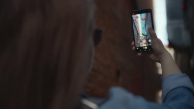 Sokakta yürüyen ve telefonuyla video çeken bir kadın. Yavaş çekim.