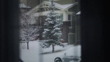 Kışın banliyö caddesinde kar yağarken pencere manzarası. Yavaş çekim.