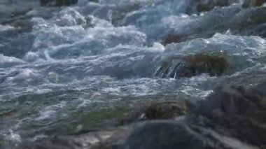 Dağ nehri taşların arasından akıyor. Yavaş çekim.