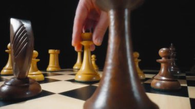 Oyuncu, satranç oyununda beyaz ile siyah veziri yere seriyor. Dolly makro çekim, yavaş çekim.