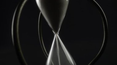 Siyah zemin üzerine kum dökülen kum saatleri. Soyut.