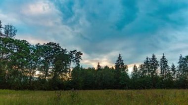 Günbatımı gökyüzü hareketli, 4k zaman dilimi çayırlı, ormanlık ve renkli günbatımı gökyüzü. Yüksek kalite 4k görüntü