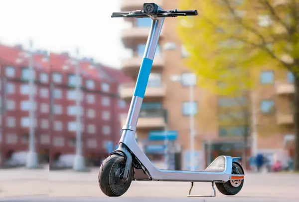A motor vehicle with wheels and tires, commonly known as a scooter, is parked on the sidewalk in front of a building