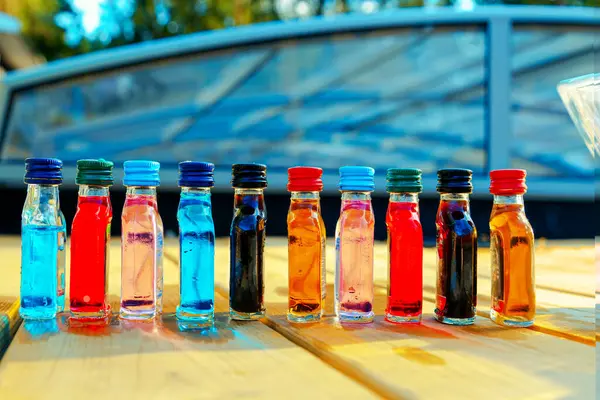 A colorful array of small bottles containing various tinted liquids in glass and plastic bottles, perfect for recreation and adding vibrancy to any setting