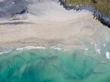 Aerial overhead shot of Kvalvika Beach in Lofoten, Norway, during spring on a clear day with clouds