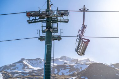 Güneşli bir kış gününde kar kaplı dağlarla bir kayak merkezinde sandalye kaldırmak