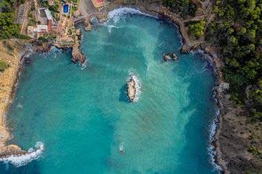Güneşli bir yaz günü mavi gökyüzü ve turkuaz suyla birlikte İbiza adasındaki Cala Xarraca sahillerinin havadan çekilmiş fotoğrafları.