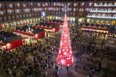 Madrid, İspanya - 12 Aralık 2023: Madrid 'in merkezinde Plaza Belediye Başkanı' nın manzarası, Noel ağacı kırmızıyla aydınlatılmış, Noel ağacı, tipik kırmızı kabinler ile Noel pazarı