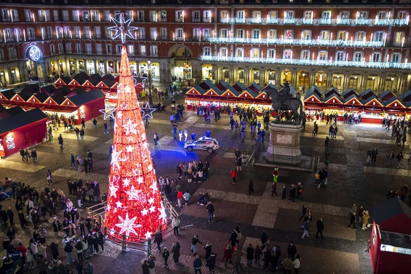 Madrid, İspanya - 12 Aralık 2023: Madrid 'in merkezinde Plaza Belediye Başkanı' nın manzarası, Noel ağacı kırmızıyla aydınlatılmış, Noel ağacı, tipik kırmızı kabinler ile Noel pazarı