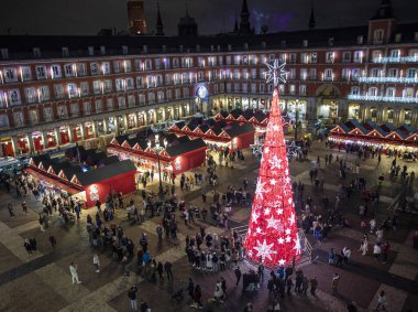 Madrid, İspanya - 12 Aralık 2023: Madrid 'in merkezinde Plaza Belediye Başkanı' nın manzarası, Noel ağacı kırmızıyla aydınlatılmış, Noel ağacı, tipik kırmızı kabinler ile Noel pazarı