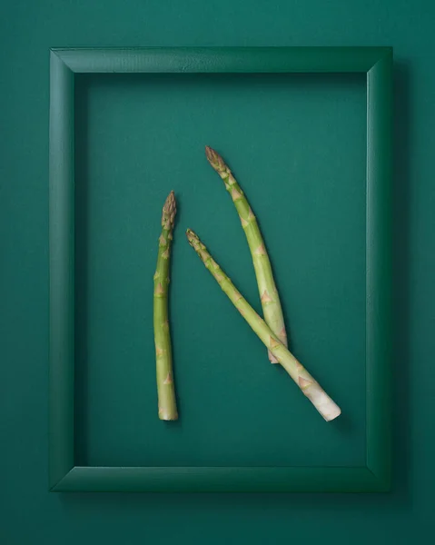 緑の背景の木枠の中のアスパラガス ロイヤリティフリーのストック画像