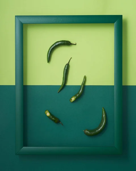 双色调绿色背景木制画框中的完整辣椒和切碎辣椒 图库照片